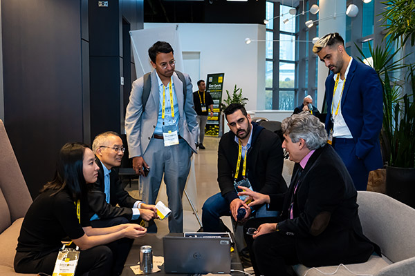 A group of people having a discussion around a laptop in a common area at the event.