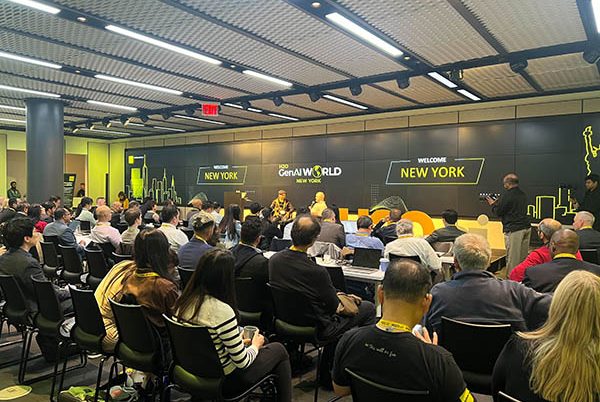 a large conference room filled with an audience watching the speakers in the front of the room.